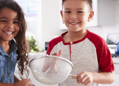 Kids smiling together as they make a Thanksgiving snack.