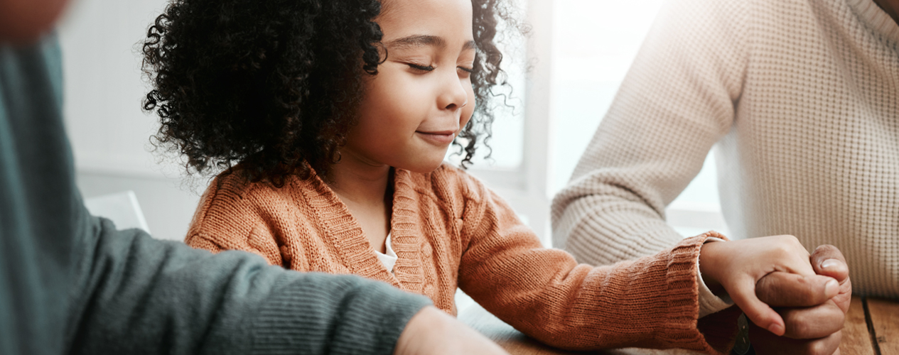 A young girl prayers with her family.