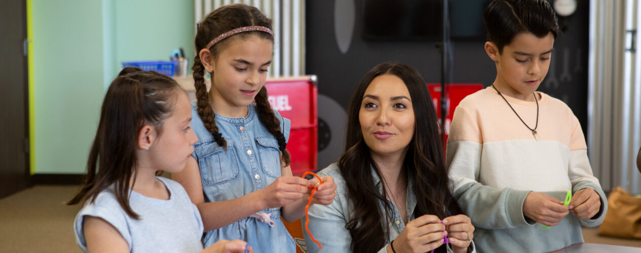 Kids and a leader twist chenille wires to make St. Patrick's Day shamrock crafts.