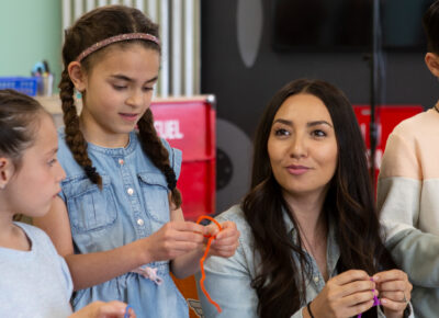 Kids and a leader twist chenille wires to make St. Patrick's Day shamrock crafts.