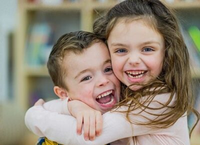 two kids hugging one another and smiling