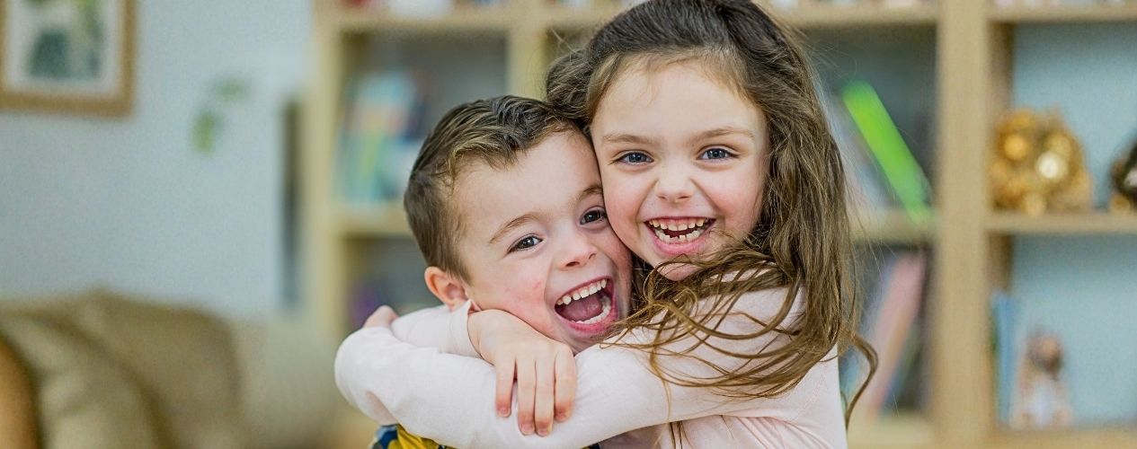 two kids hugging one another and smiling