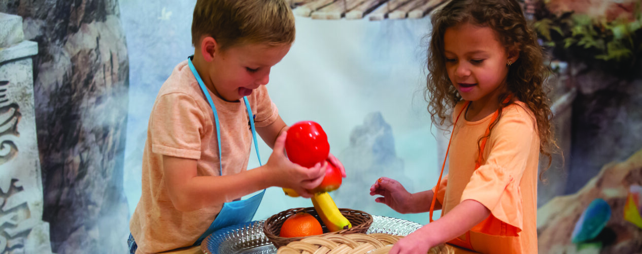 Two preschool age kids play with fake food.
