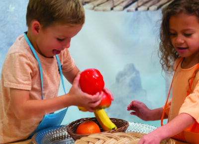 Two preschool age kids play with fake food.