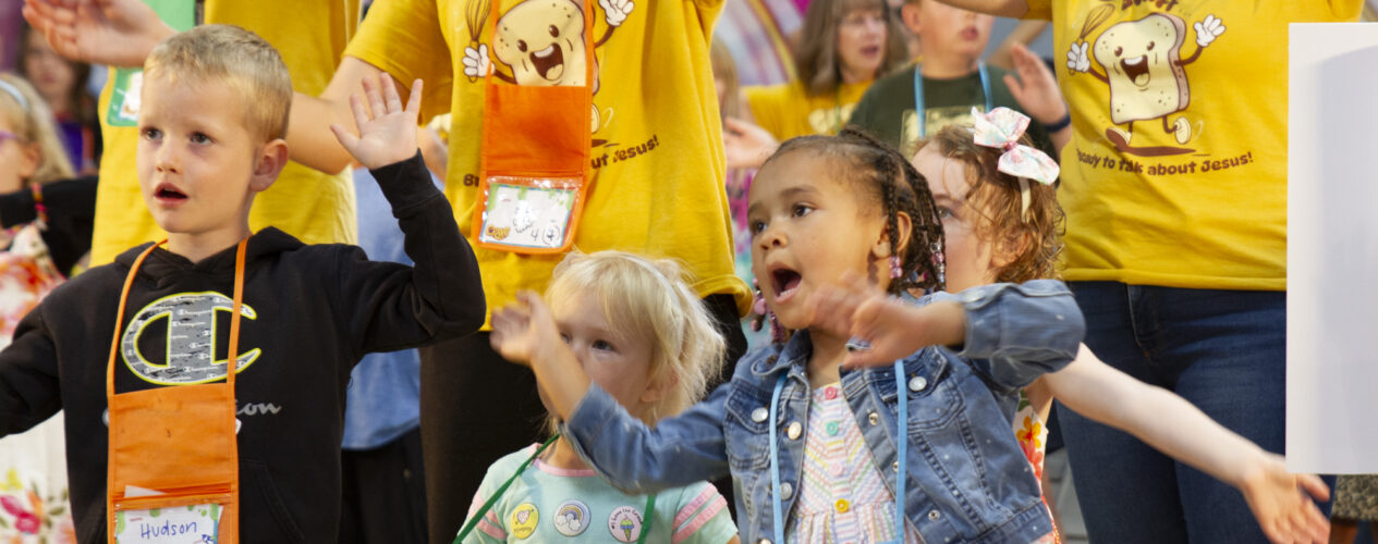 Kids in children's ministry waving their hands during a loud, exciting worship session.