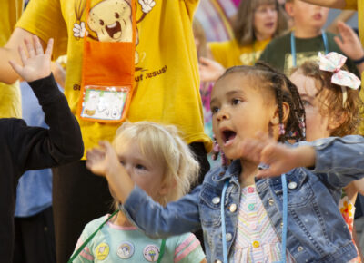 Kids in children's ministry waving their hands during a loud, exciting worship session.