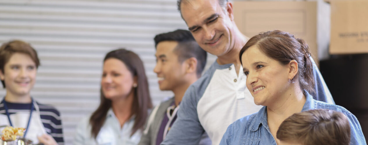 family at a church or community lunch gathering. A woman and man are smiling.
