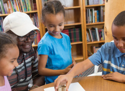 kids and children's ministry leader in a small church setting gathered around a table working on an object lesson.
